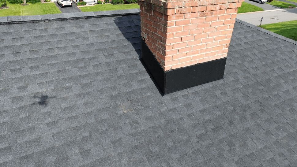 Chimney Flashing and Shingles | Tycos Roofing And Siding Inc Brick chimney with sealed flashing on a gray shingle roof.