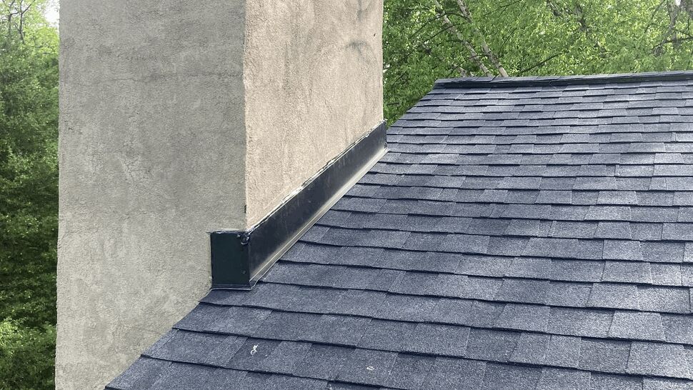 Roof detail showing chimney with metal flashing on shingle roof