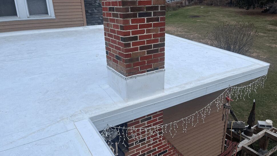 Brick chimney on flat roof with flashing and roof edge details