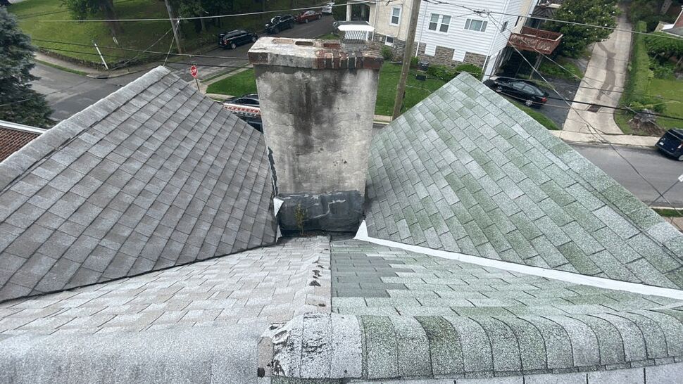 Aerial shot of a chimney surrounded by roofs with different shingle colors.