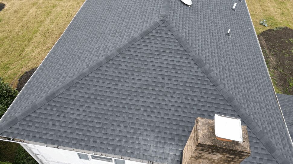 Drone close-up of chimney and roof ridge with satellite dish and vents.