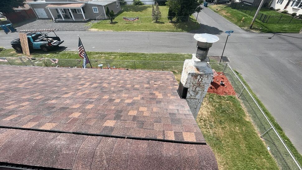 Shingle roof with a chimney cap seen from above looking toward the street.