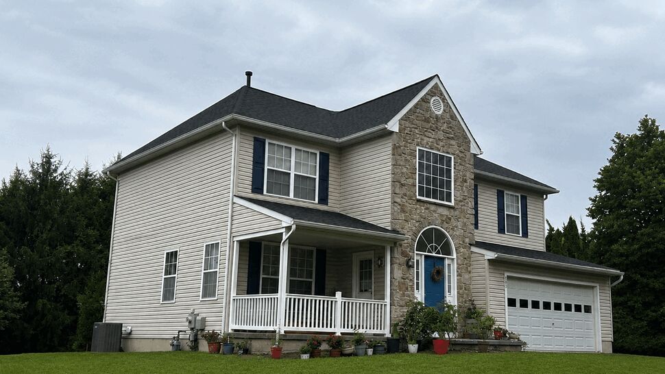 Two-story home with stone entry, blue door, porch and vinyl siding