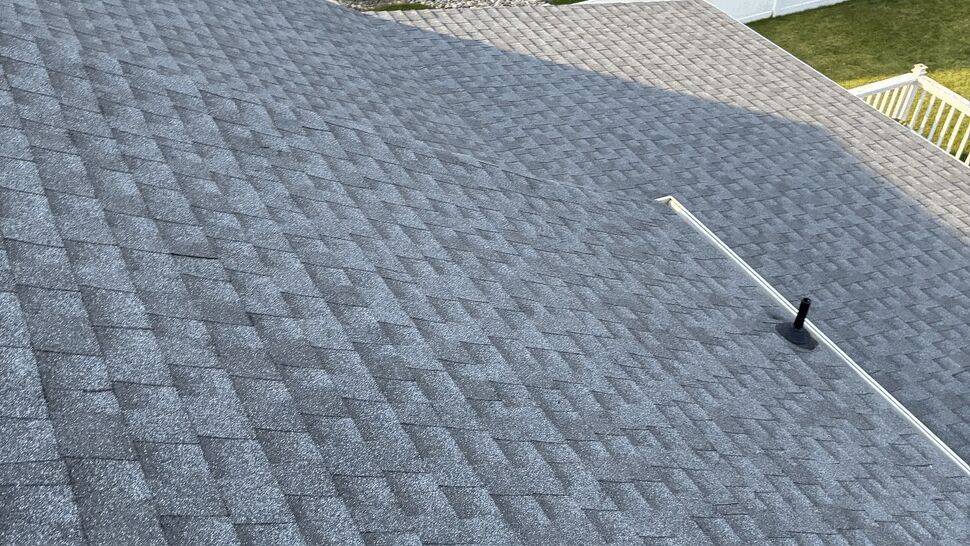 Close-up of clean gray asphalt shingles on a steep roof slope with vents.