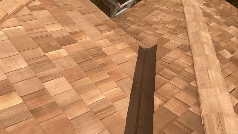 Close-up of cedar shake roof valley with metal flashing and ridge caps