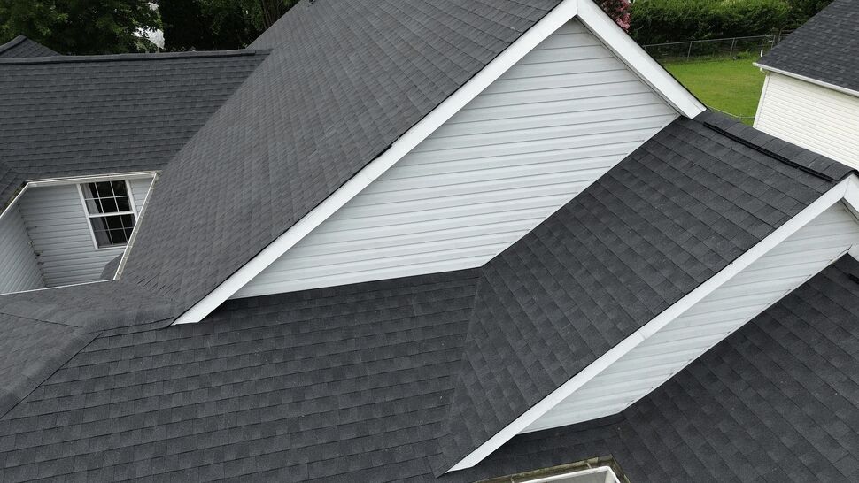 Close-up of roof intersections and white gable siding detail.