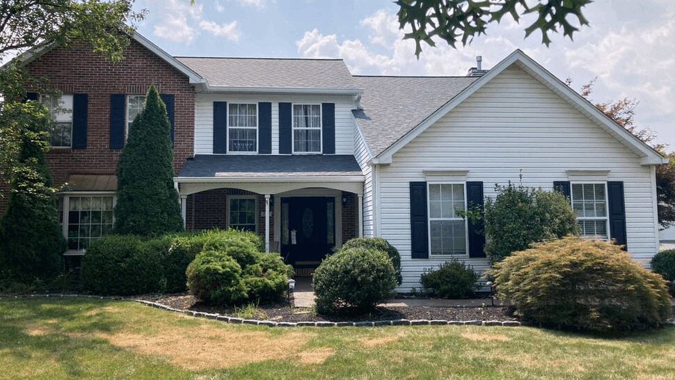 Two-story colonial home with brick and white siding and a dark shingle roof.