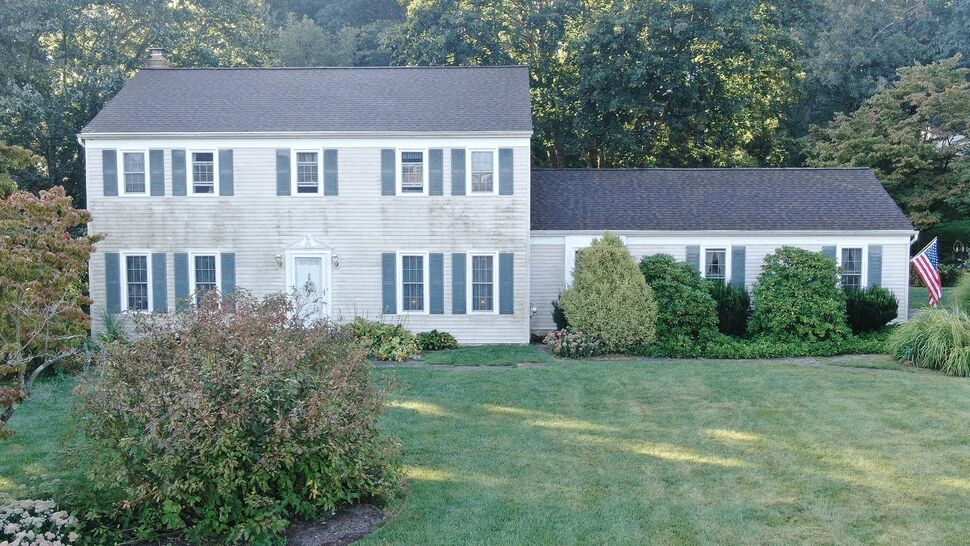 Front view of colonial house with white siding, shutters and dark shingle roof