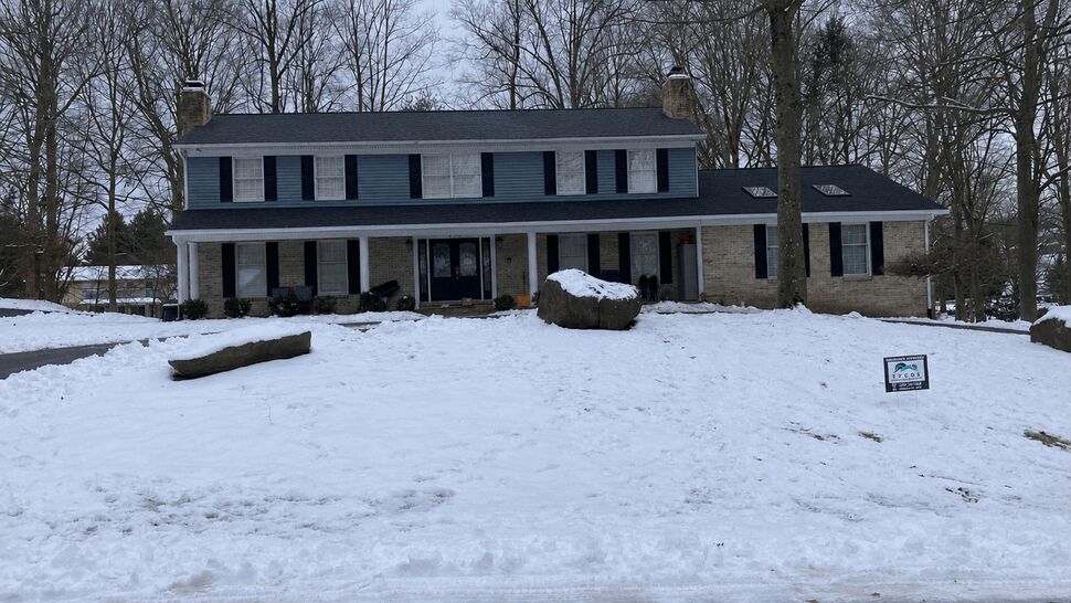 Two-story colonial home with a dark shingle roof and snow-covered front lawn