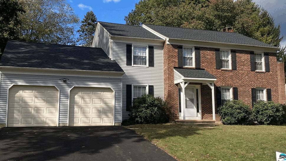 Front view of colonial house with new dark roof and two-car garage