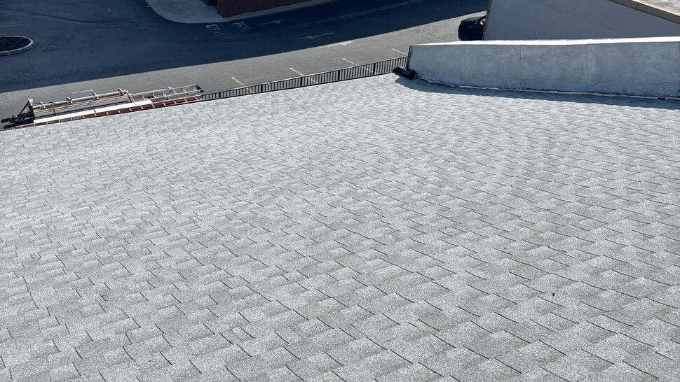 Sloped shingle roof with a commercial building in the background.