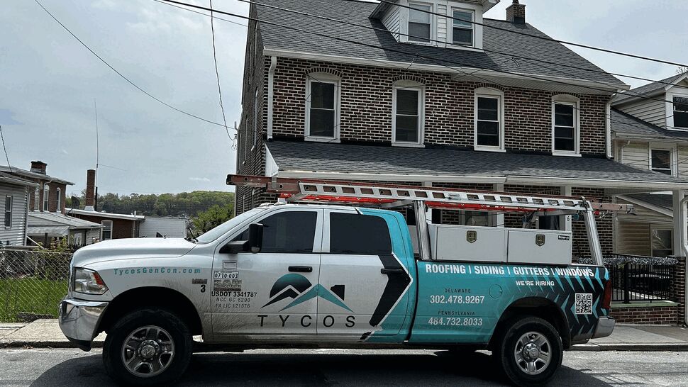 Tycos Roofing And Siding Inc pickup truck parked in front of a brick home.