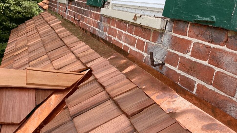 Copper Flashing and Cedar Shingles | Tycos Roofing And Siding Inc Close-up of cedar shakes and newly installed copper flashing along masonry