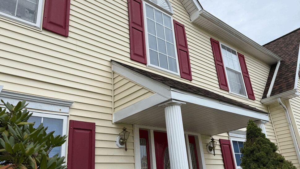 Covered Entry Siding Detail | Tycos Roofing And Siding Inc Close view of cream siding, red shutters, windows, and a covered entry