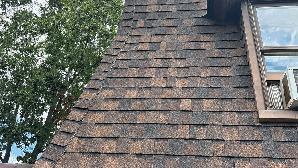 Close-up of curved mansard shingles with a black gutter below