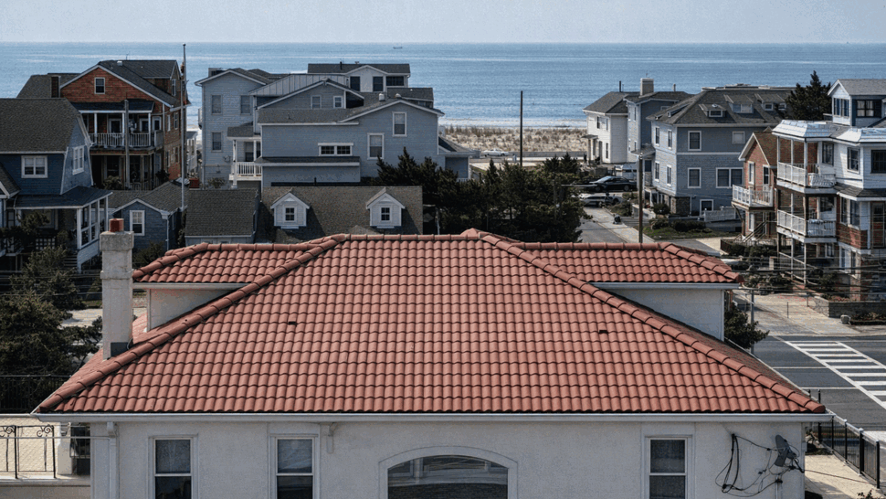 Ocean View Red Tile Roof Installation | Tycos Roofing And Siding Inc Red tile roof of an oceanfront home with beach and sea in the background