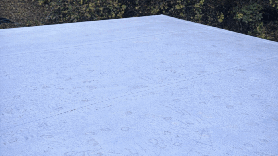 Close-up of a smooth white flat roof membrane with light markings.