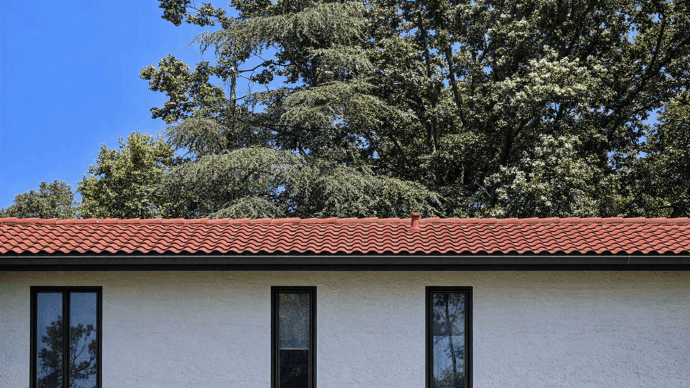 Windows beneath red tile eaves against a clear blue sky