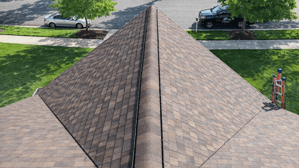 Aerial Ridge Vent Installation | Tycos Roofing And Siding Inc Aerial close-up of brown shingle ridge vent and ladder at roof peak