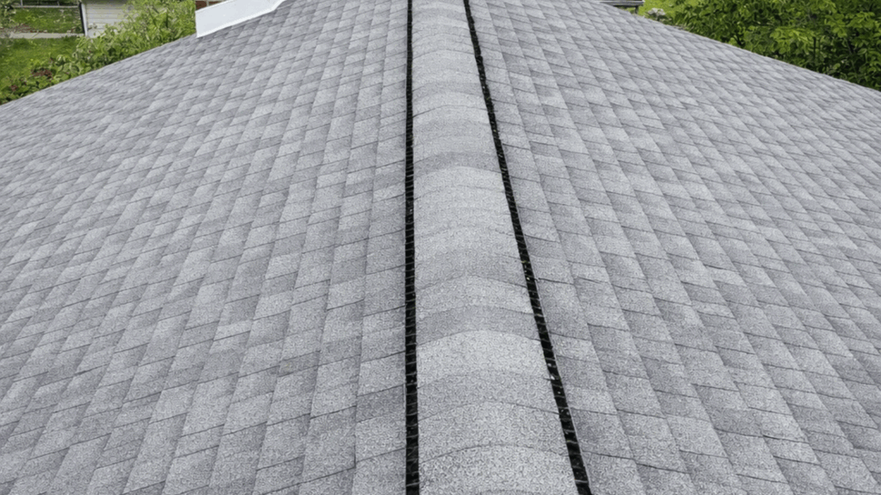 Shingle roof ridge with installed ridge vent and nearby chimneys