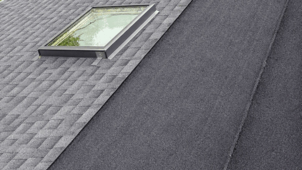 Skylight set into shingle roof next to a membrane-covered ridge transition