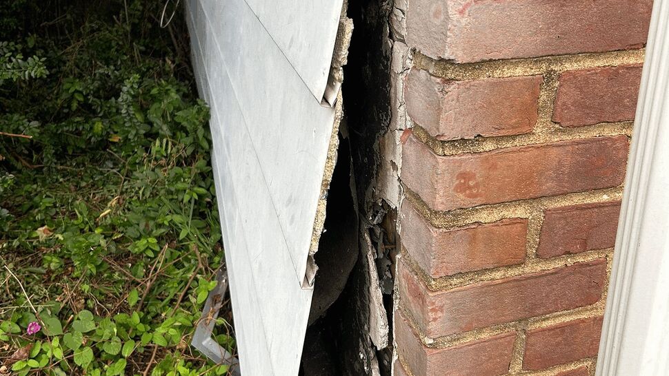 Exposed sheathing from damaged siding | Tycos Roofing And Siding Inc Siding separated from wall exposing sheathing at a brick corner