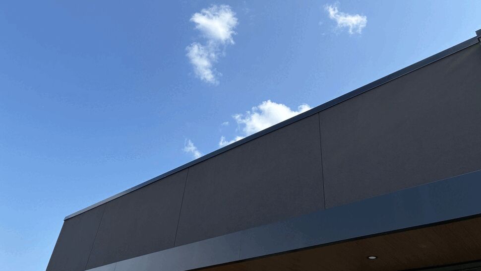 Dark exterior siding panels with wood-toned soffit beneath roof overhang