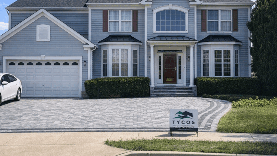 Colonial Home Exterior with New Siding | Tycos Roofing And Siding Inc Two-story colonial home with grey siding, a shingled roof, and a Tycos sign on the front lawn.