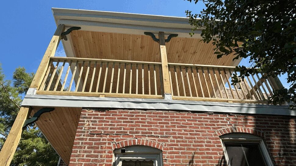 Close-up of deck railing, soffit, and gutter flashing on two-story porch.