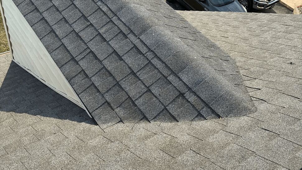 Close-up of a dormer and ridge capped with gray asphalt shingles.