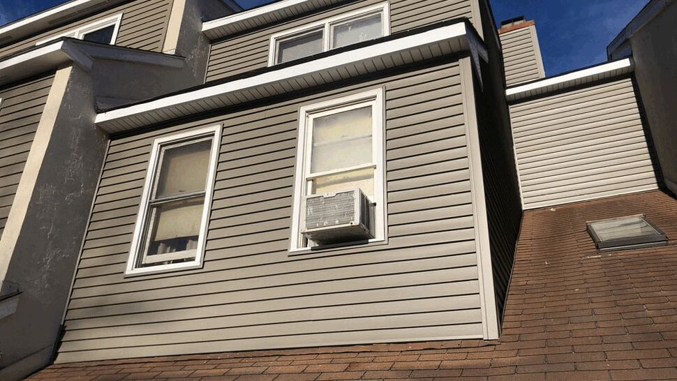 Dormer with asphalt shingles, skylight, and vinyl siding above a sloped roof.