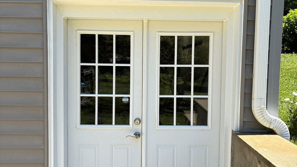 White double entry doors with divided-light windows and adjacent downspout