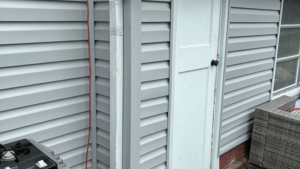 White downspout and vinyl siding beside a small exterior door