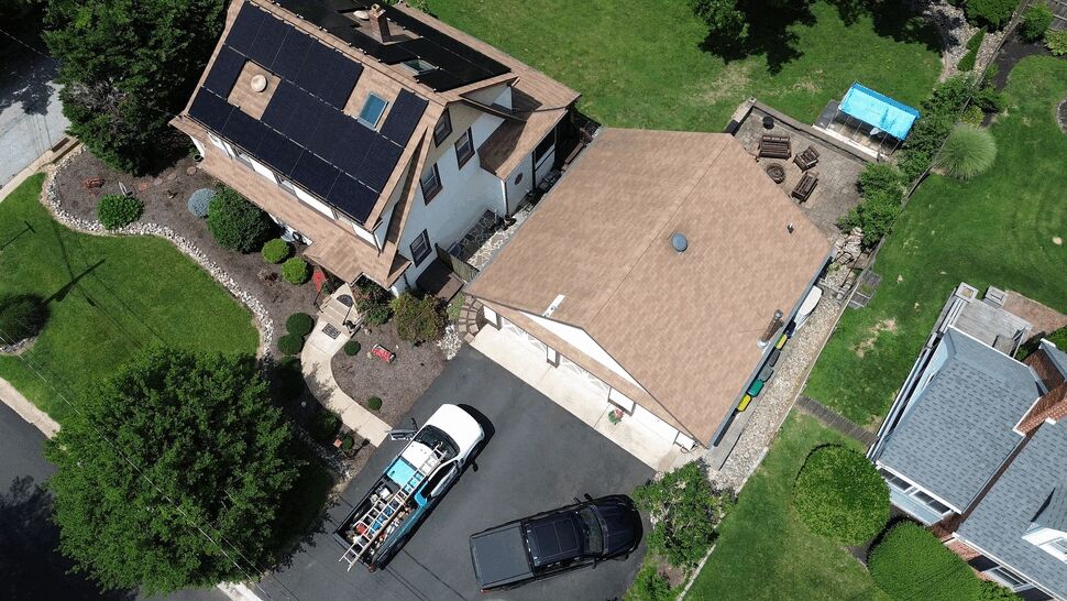 Service trucks parked in driveway beside home as roofing crew works