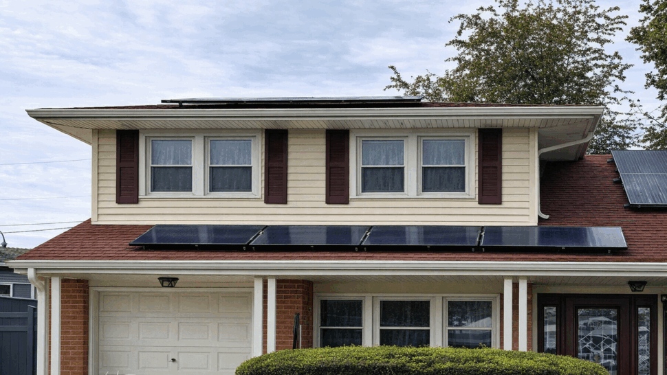 Two-story house with red roof and solar panels over the garage.