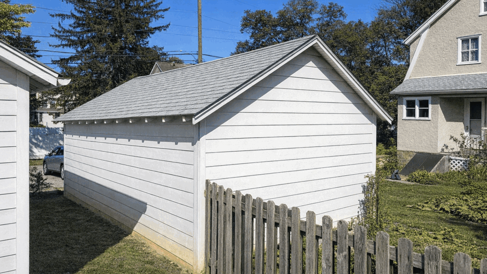 Side view of detached garage with asphalt shingle roof and white siding