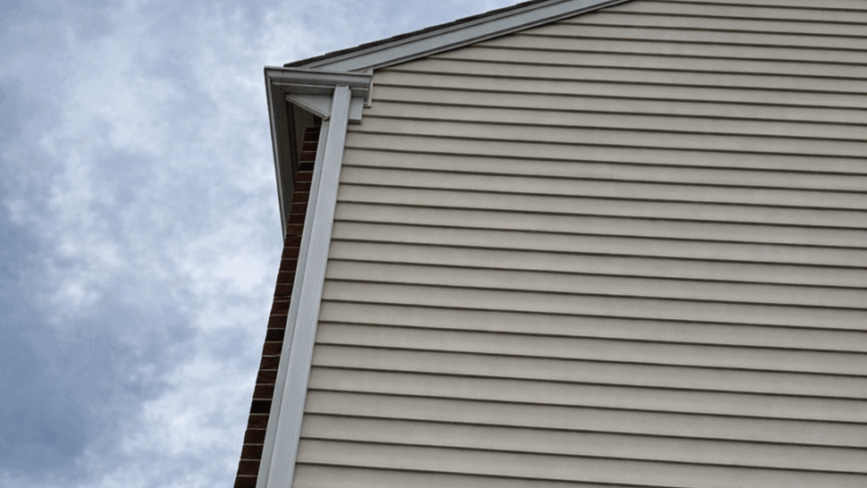 Roofline and Gutter Junction | Tycos Roofing And Siding Inc Tall vertical siding rising to the roofline with a visible gutter connection.