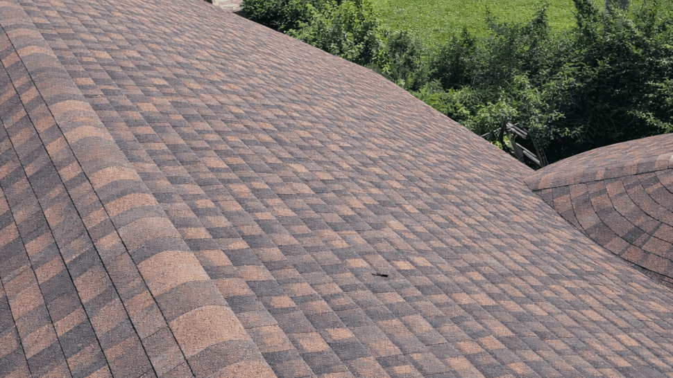 Aerial view of brown asphalt shingle roof and landscaped yard.