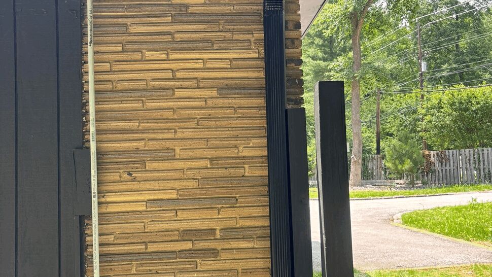 Eave Gutter and Siding Corner | Tycos Roofing And Siding Inc Corner eave showing black gutter, soffit and vertical siding trim with trees in background