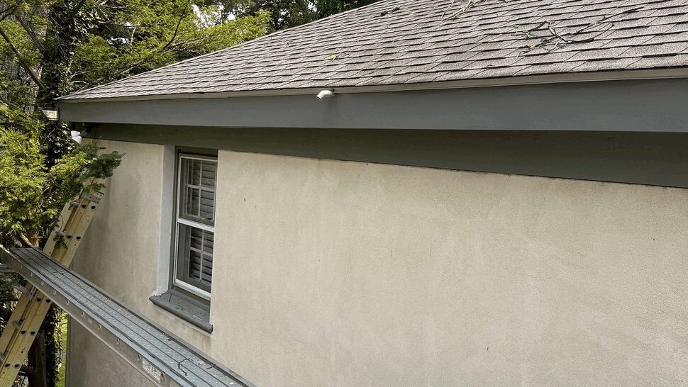 Ladder and tools on roof edge near eave for gutter work