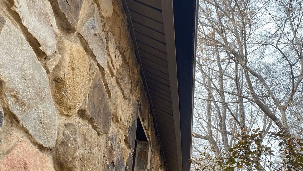 Under-eave view of soffit, gutter, and stone wall