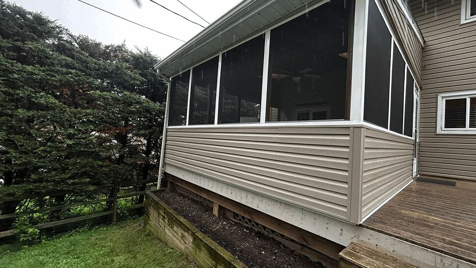 Elevated screened porch with beige siding and lawn below.