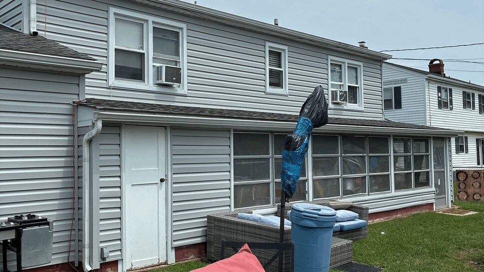 Enclosed porch with multiple windows and outdoor seating in the yard