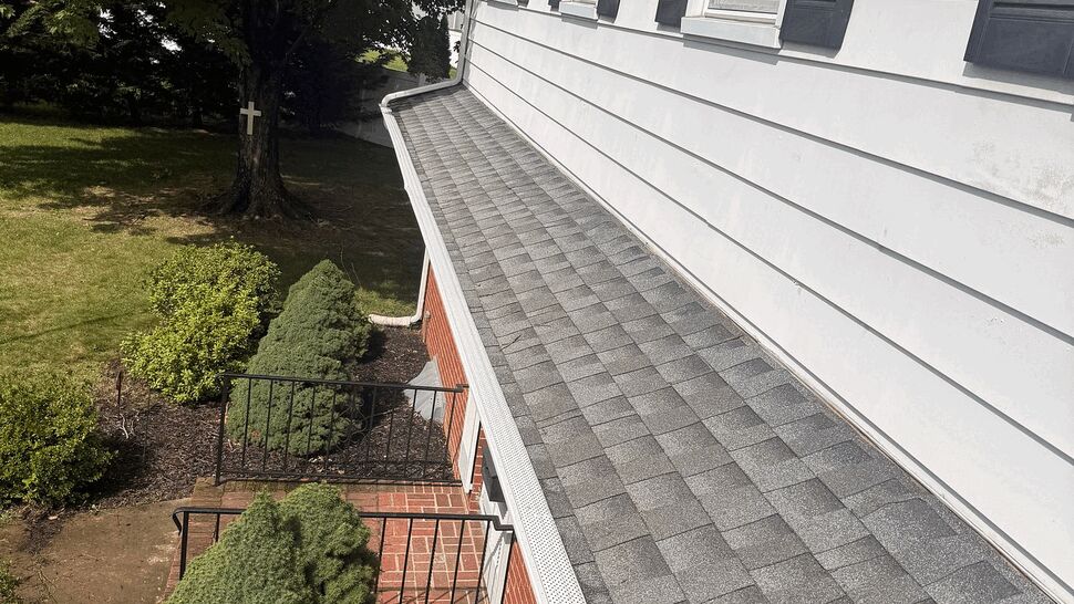 Entry roof with gutter and siding | Tycos Roofing And Siding Inc Long entry roof with grey shingles, white gutter and siding with black shutters