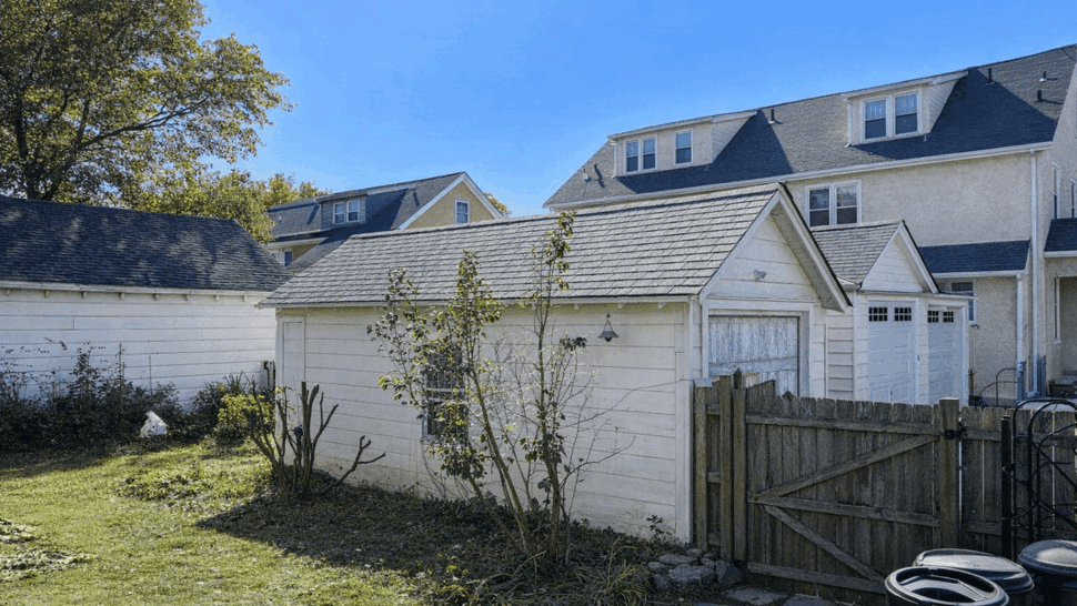 Backyard view of detached garage with white painted siding and surrounding yard