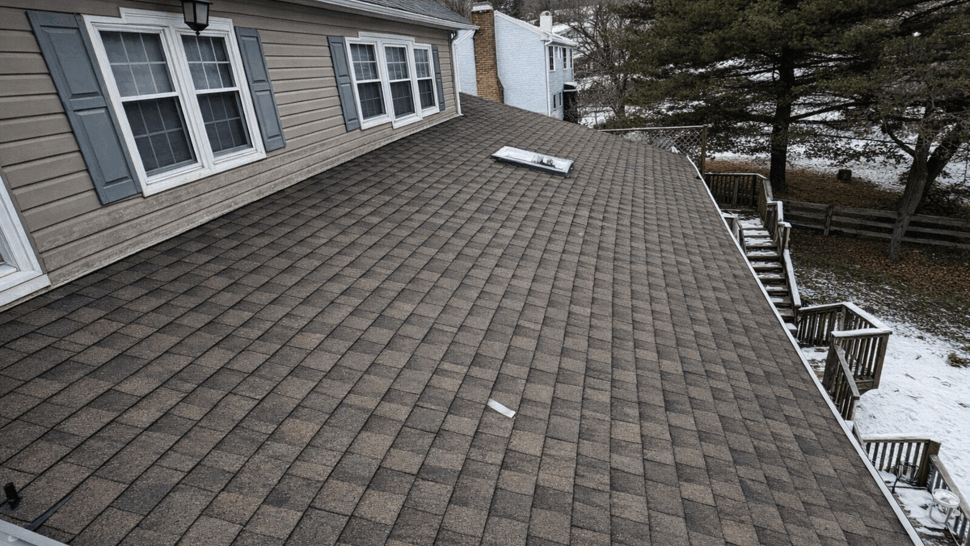 Close-up of brown shingle roof with a Velux skylight and surrounding flashing