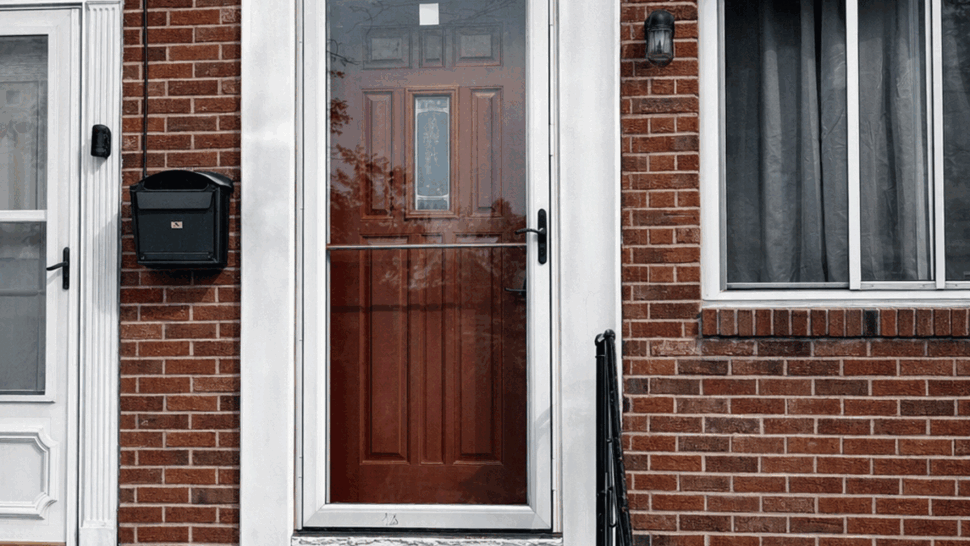 Brick front entry with red door and white storm door trim