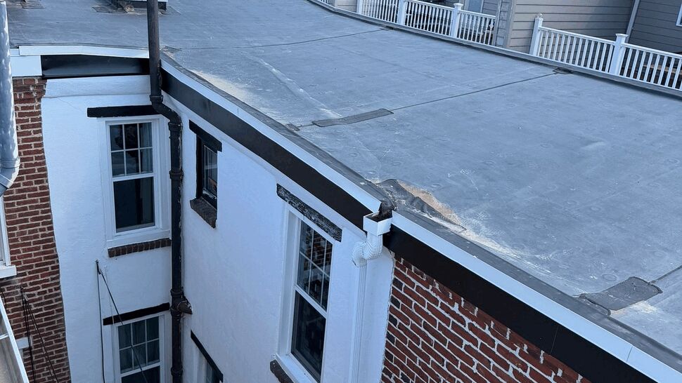 Top view of flat roof membrane with skylight and visible gutter downspout