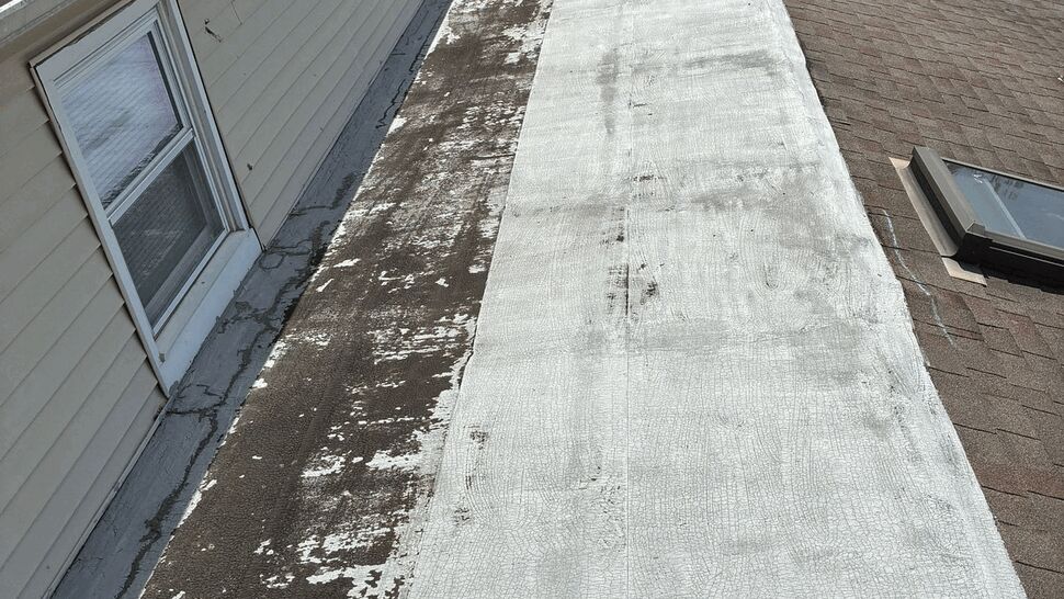 Flat Roof Prep and Wear Assessment | Tycos Roofing And Siding Inc Partially stripped flat roof surface beside house wall being prepped for repair