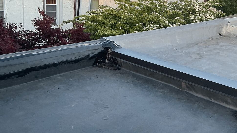 Flat rubber roof corner with parapet and neighboring buildings